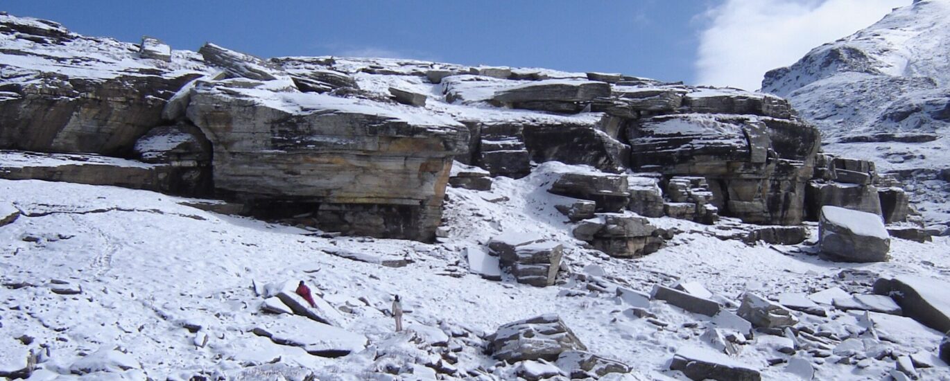 A serene snow-covered landscape at Rohtang Pass, captured in 2014, featuring rugged rock formations and pristine white snow under a clear blue sky.